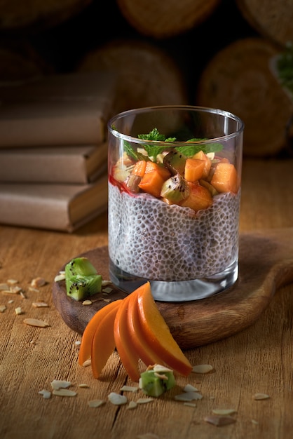 Yaourt dessert aux graines de chia et kaki de fruits sur un fond sombre en bois. Végétalien sain, table de petit déjeuner végétarien, ingrédients sur la table