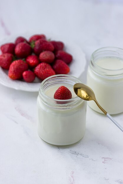 Yaourt fait maison Pots de yaourt et de fraises sur un tableau blanc Une bonne nutrition