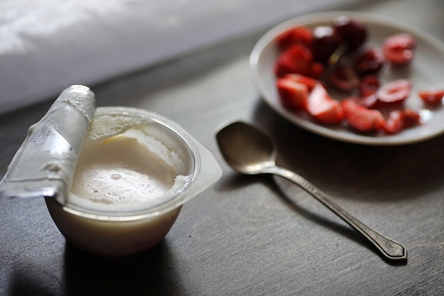 Yaourt avec fraises et cerises juteuses fraîches sur une table en bois