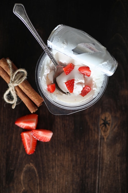 Yaourt avec fraises et cerises juteuses fraîches sur une table en bois