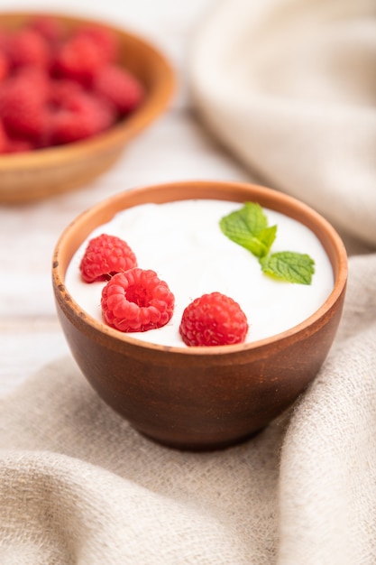 Yaourt à la framboise dans des tasses d'argile sur bois blanc