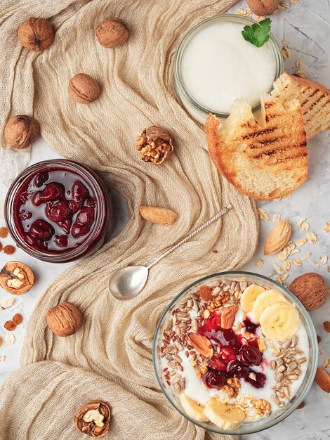 Yaourt avec granola, noix et confiture de cerises dans un bol