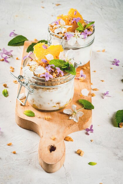 Yaourt avec granola, orange, menthe et fleurs comestibles