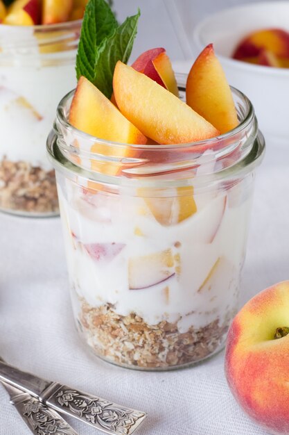 Yaourt avec granola et pêches dans des verres