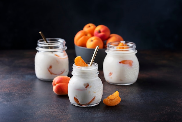 Yaourt sucré sain aux abricots sur la table sombre, image de mise au point sélective