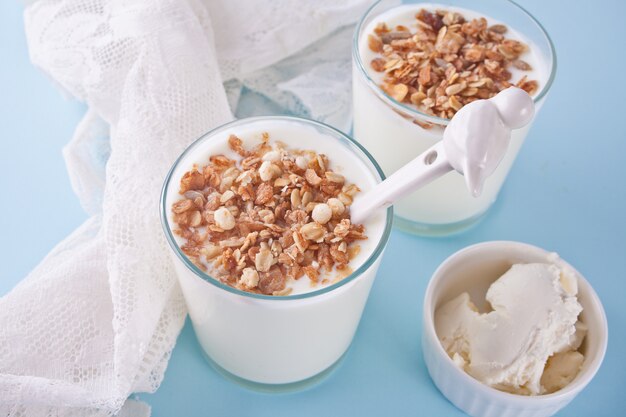 Yaourt en verre avec muesli, fromage à la crème sur une table avec une serviette blanche.