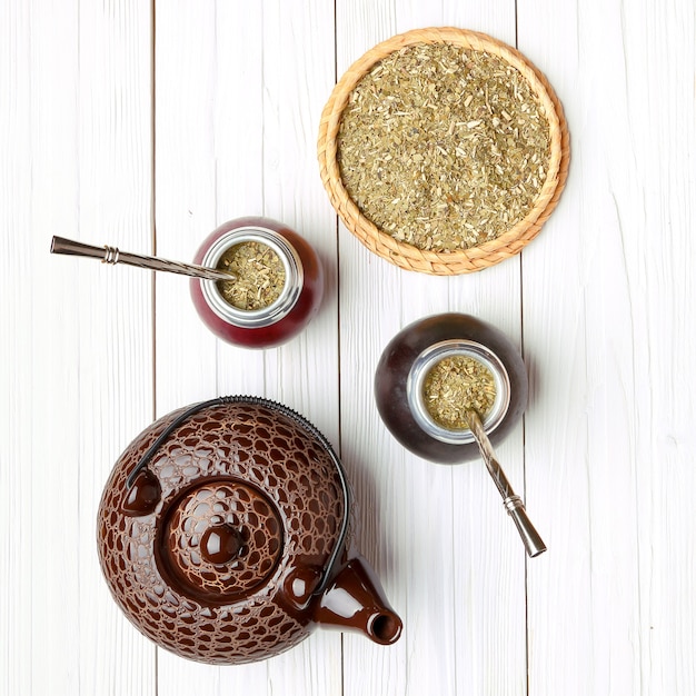 Yerba mate et calebasses sur fond de bois clair, vue de dessus