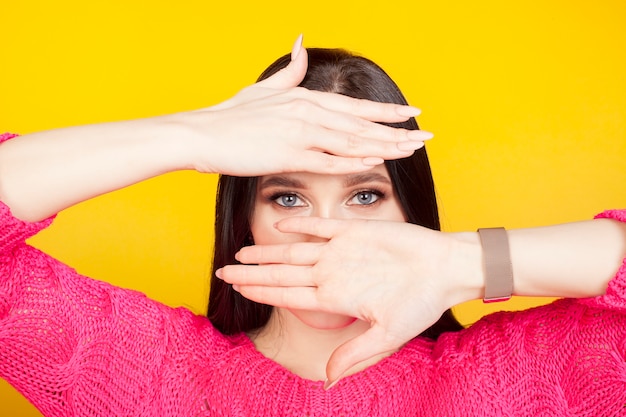 Yeux bleus d'une femme, illuminés par les paumes couvrant la partie supérieure du front et la partie inférieure du visage. Le concept des yeux brillants, du maquillage cosmétique et du mascara.