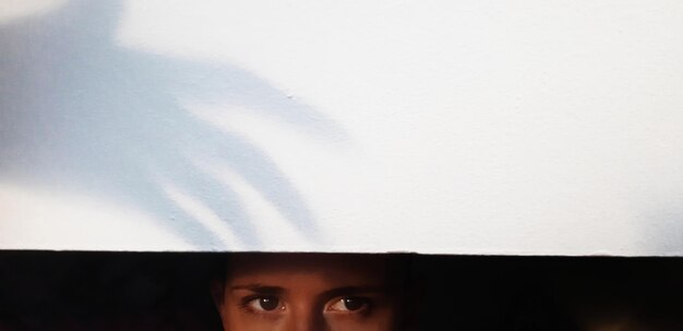 Photo des yeux de femme regardant sous un mur noir avec une ombre de main effrayante