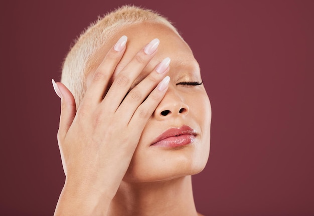 Yeux fermés mains et soins de la peau du visage de la femme en studio isolé sur une maquette de fond rouge Dermatologie maquillage cosmétiques et beauté du modèle féminin satisfait après un traitement facial pour une peau saine