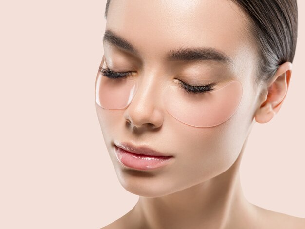 Les yeux masquent les cosmétiques pour le visage d'une femme asiatique. Fond de couleur. Rose