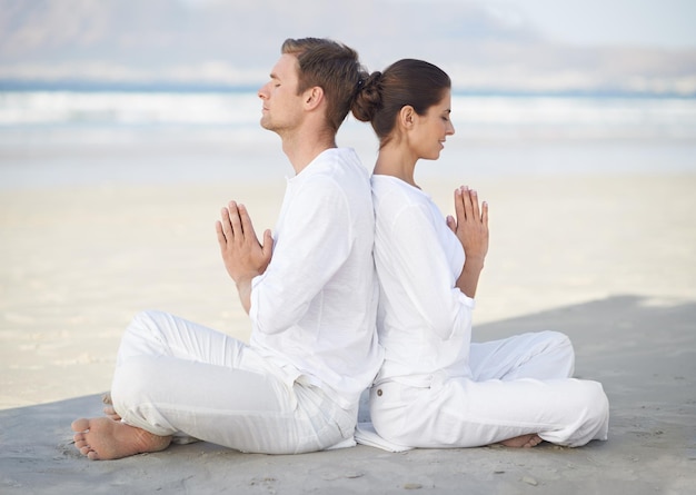 Yoga en bord de mer Un jeune couple pratiquant le yoga sur la plage