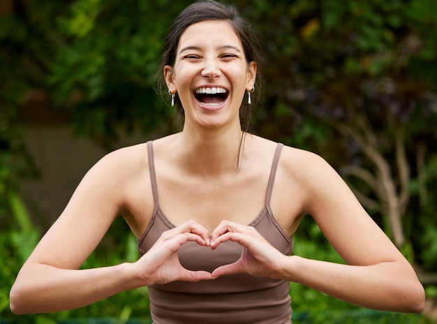 Le yoga consiste à se rapprocher des bonnes vibrations Portrait d'une jeune femme faisant une forme de coeur avec ses mains tout en faisant de l'exercice à l'extérieur