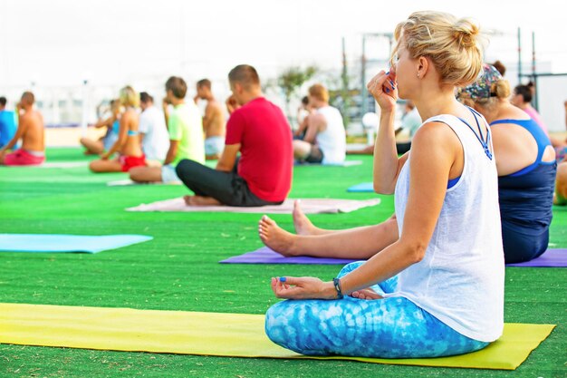 Yoga dans le parc jeune femme faisant des exercices avec un groupe de personnes d'âge mixte