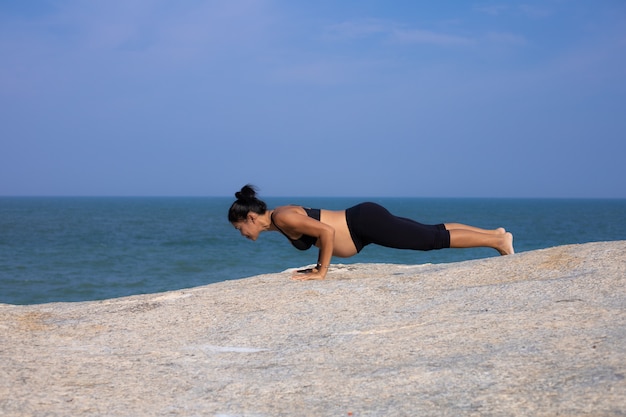 Yoga femme asiatique enceinte sur l'heure d'été coucher de soleil sur la plage