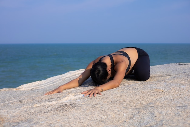 Yoga femme asiatique enceinte sur l'heure d'été coucher de soleil sur la plage