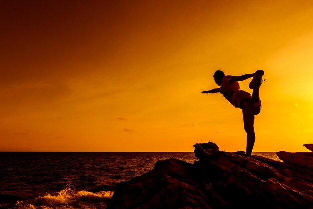 Yoga femme silhouette sur le coucher de soleil sur la montagne. Sport et mode de vie sain.