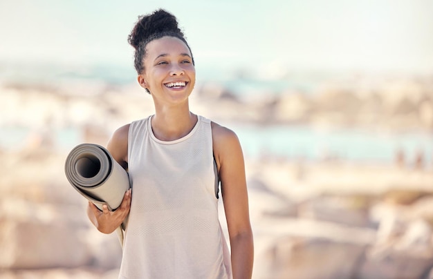 Photo yoga fitness et plage femme noire pensant à la méditation ou au style de vie zen sous le soleil d'été pour la guérison en plein air, le bien-être et la paix sports pilates et femme en bonne santé avec équipement d'entraînement au bord de la mer