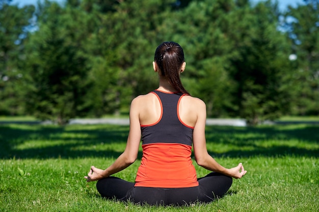 Yoga. Jeune femme pratiquant la méditation de yoga dans la nature au parc. posture du lotus. Concept de mode de vie de santé.