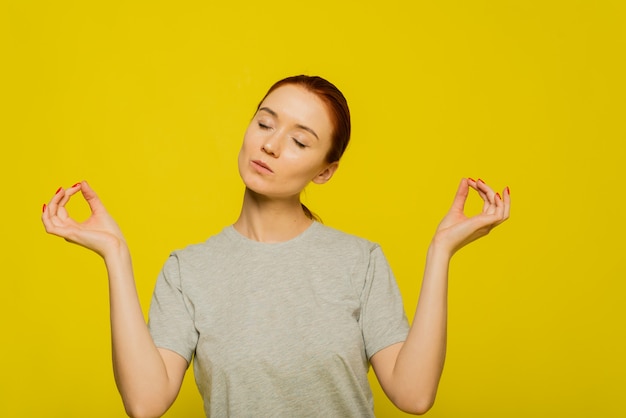 Yoga et méditation. Belle jeune femme rousse habillée avec désinvolture en gardant les yeux fermés en méditant