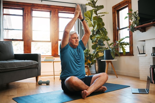 Yoga méditation et bien-être avec un homme zen suivant un cours en ligne pour l'exercice de fitness et l'entraînement à la maison Retraite senior et santé avec un retraité âgé s'exerçant dans sa maison