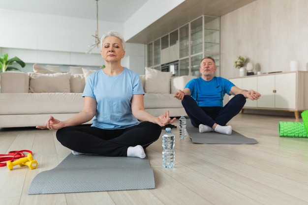 Yoga méditation de pleine conscience adulte âgé couple mature pratiquant le yoga à la maison mari âgé d'âge moyen