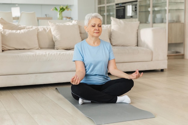 Yoga méditation pleine conscience adulte âgé femme mature pratiquant le yoga à la maison vieille dame d'âge moyen