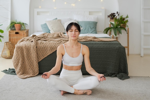 Yoga méditation pleine conscience jeune femme en bonne santé pratiquant le yoga dans le salon à la maison femme assise