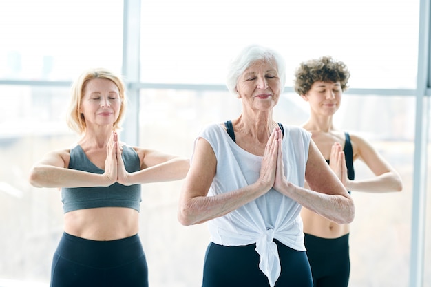 Yoga relaxant. Groupe de femmes méditant à côté d'une grande fenêtre