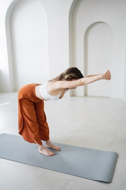 Yoga sur le tapis d'entraînement dans un club de remise en forme une femme fait de l'asana pose de l'aérobic et de la gymnastique