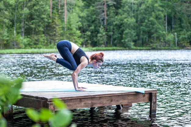 Yogi fille pratiquant le yoga faisant l'exercice Bakasana Pose de grue sur le lac Concept de vie saine et d'équilibre naturel