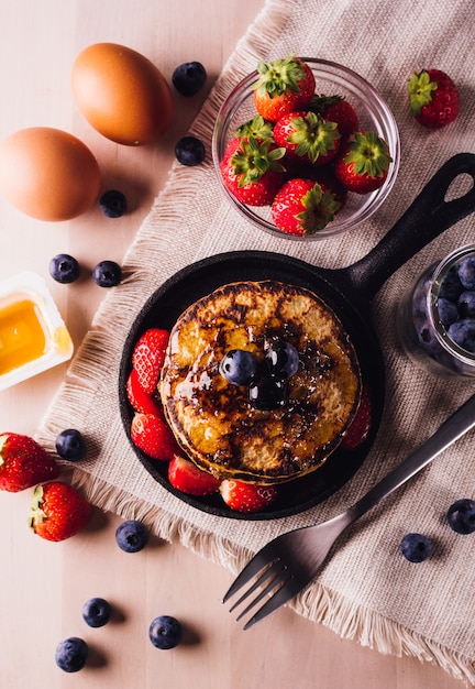 Yop vue de pile de crêpes faites maison avec des bleuets et des fraises, parfait pour le petit déjeuner