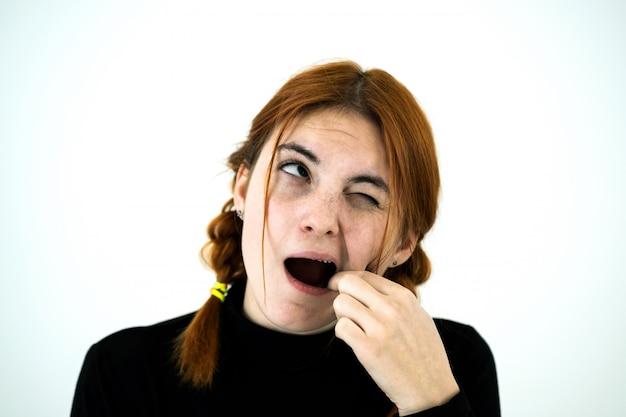 Youn femme à bouche ouverte creusant avec ses doigts pour quelque chose coincé dans les dents après avoir mangé.