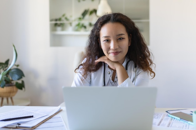 Youn médecin asiatique à l'aide d'un ordinateur portable et assis au bureau