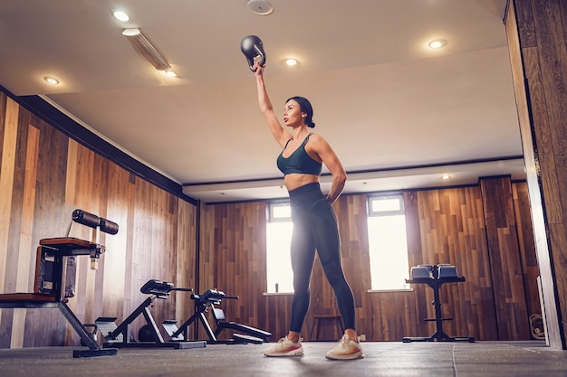 Young adult fitness woman doing swing exercice avec un kettlebell dans le cadre d'une séance d'entraînement de remise en forme