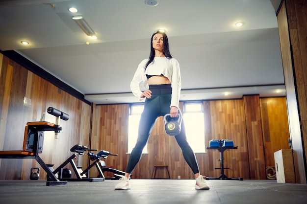 Young adult fitness woman doing swing exercice avec un kettlebell dans le cadre d'une séance d'entraînement de remise en forme