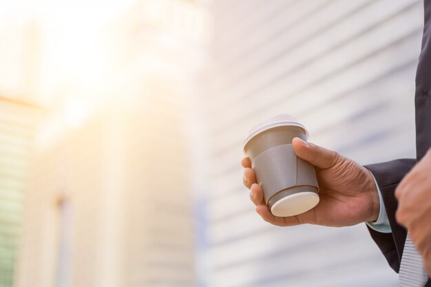 Young Asia bel homme d&#39;affaires, boire du café chaud dans la ville moderne.