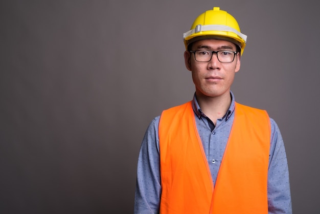 Young Asian man construction worker contre mur gris