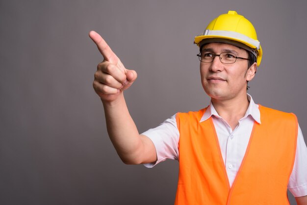 Young Asian man construction worker portant des lunettes contre g