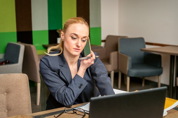 Young caucasian businesswoman talking by smartphone travaillant au bureau à domicile