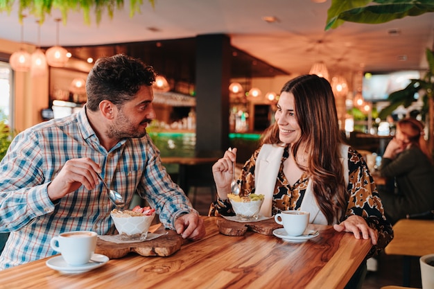 Young Caucasian couple prenant le petit déjeuner un café colombien et un yaourt aux fruits pour un régime dans un restaurant