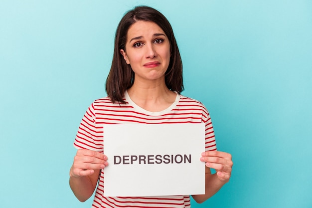 Young caucasian woman holding dépression placard isolé sur fond bleu