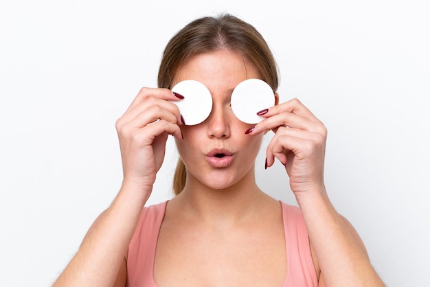 Young caucasian woman isolé sur fond blanc avec un coton pour enlever le maquillage de son visage