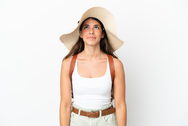 Young caucasian woman wearing a Pamela en vacances d'été isolé sur fond blanc et levant