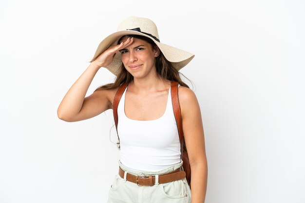 Young caucasian woman wearing a Pamela en vacances d'été isolé sur fond blanc à loin avec la main pour regarder quelque chose