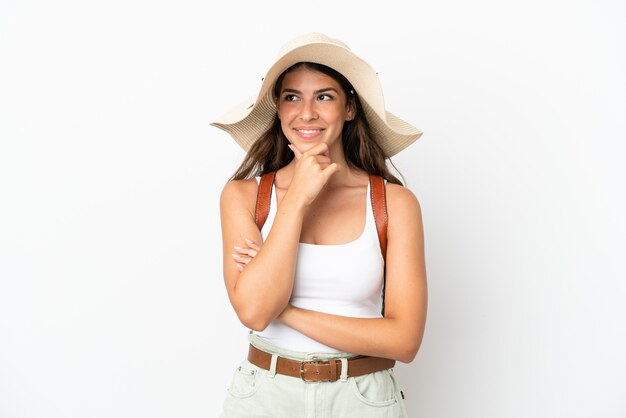 Young caucasian woman wearing a Pamela en vacances d'été isolé sur fond blanc à la recherche sur le côté