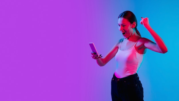 Young caucasian womans portrait sur fond de studio dégradé bluepurple en néon