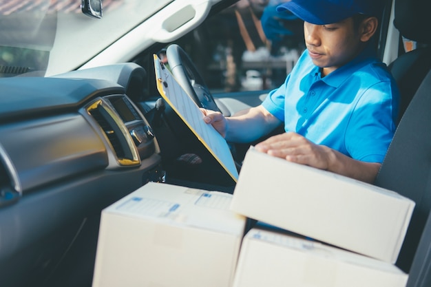 Young Delivery Man Vérification de la liste des clients sur le presse-papiers.