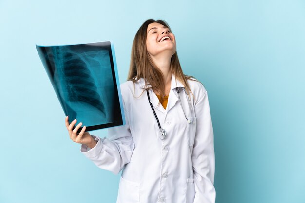 Young doctor woman holding radiographie sur fond isolé en riant