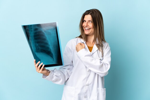 Young doctor woman holding radiographie sur isolé célébrant une victoire